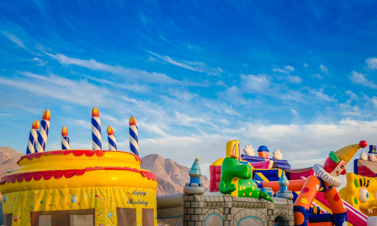 Colorful inflatable jumping castles for kids in the children's park under a blue sky.